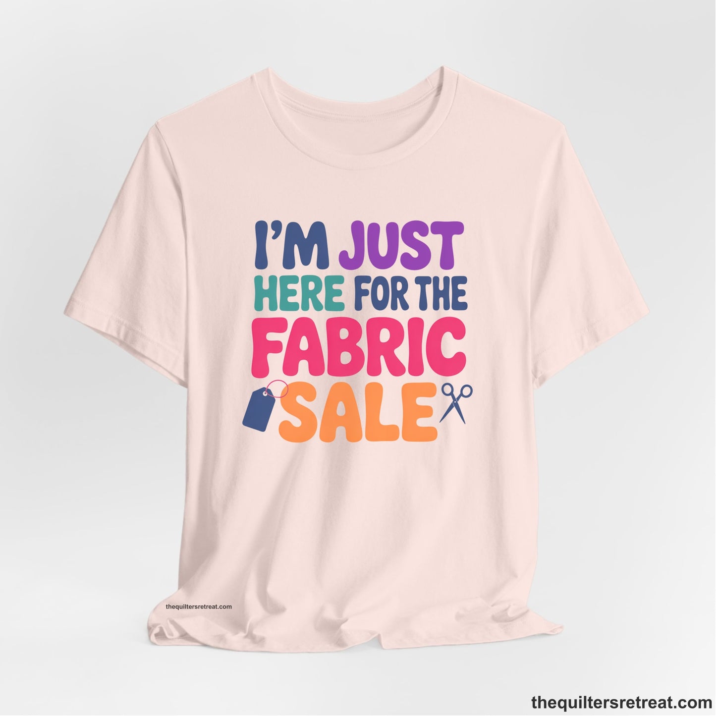 A Soft Pink Short Sleeve T-Shirt with a playful "I'm Just Here for the Fabric Sale" text with colorful letters and sewing icons