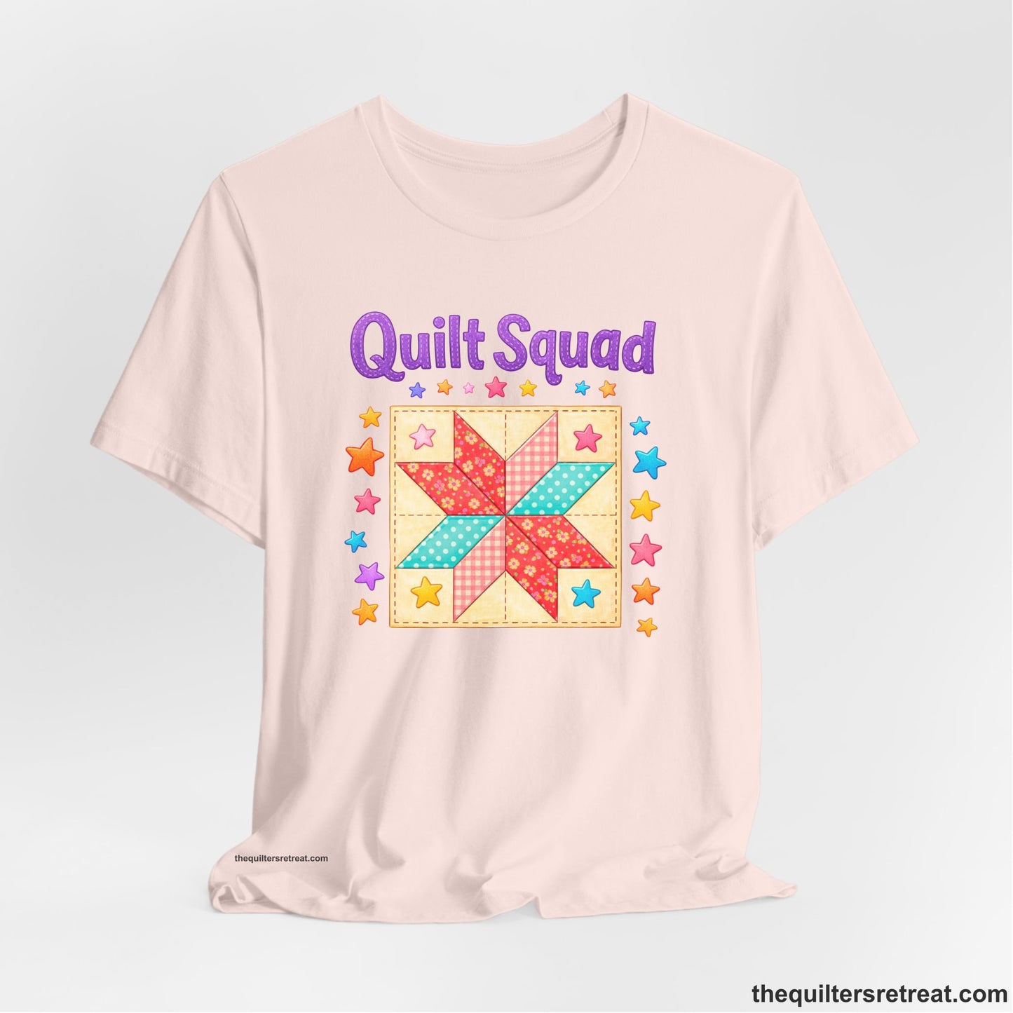 A Soft Pink Short Sleeve T-Shirt with a Patchwork quilt star with colorful stars, playful mood, "Quilt Squad" text.