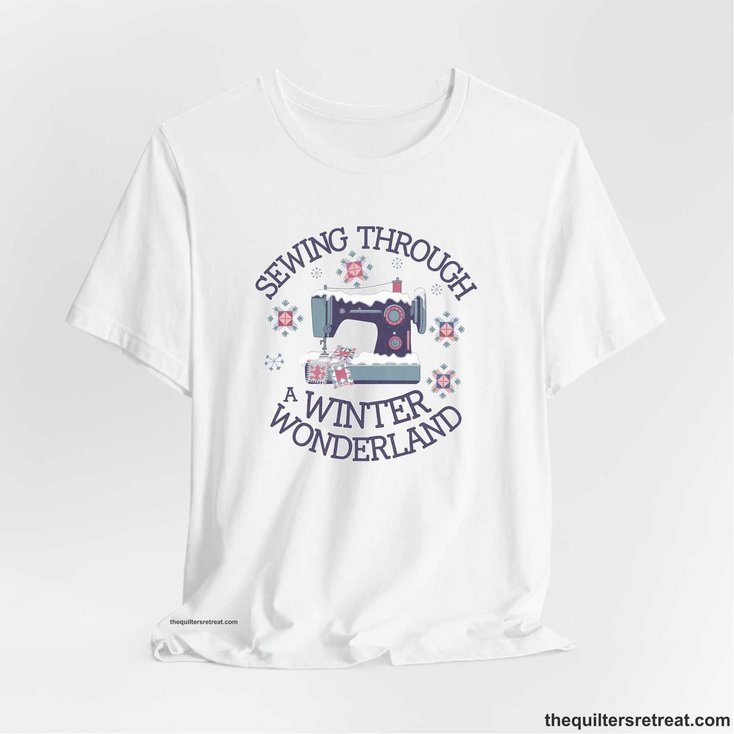 A White Short Sleeve T-Shirt with a sewing machine covered in snow with festive quilting elements and "Sewing Through a Winter Wonderland" text