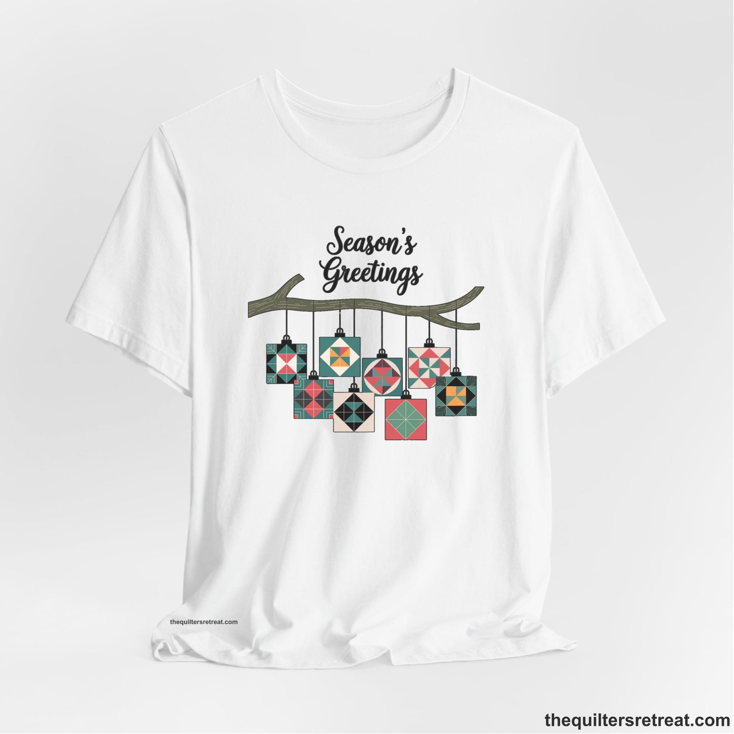 A White Short Sleeve T-Shirt with a season's greetings text above colorful quilt block ornaments on tree branch in rustic style