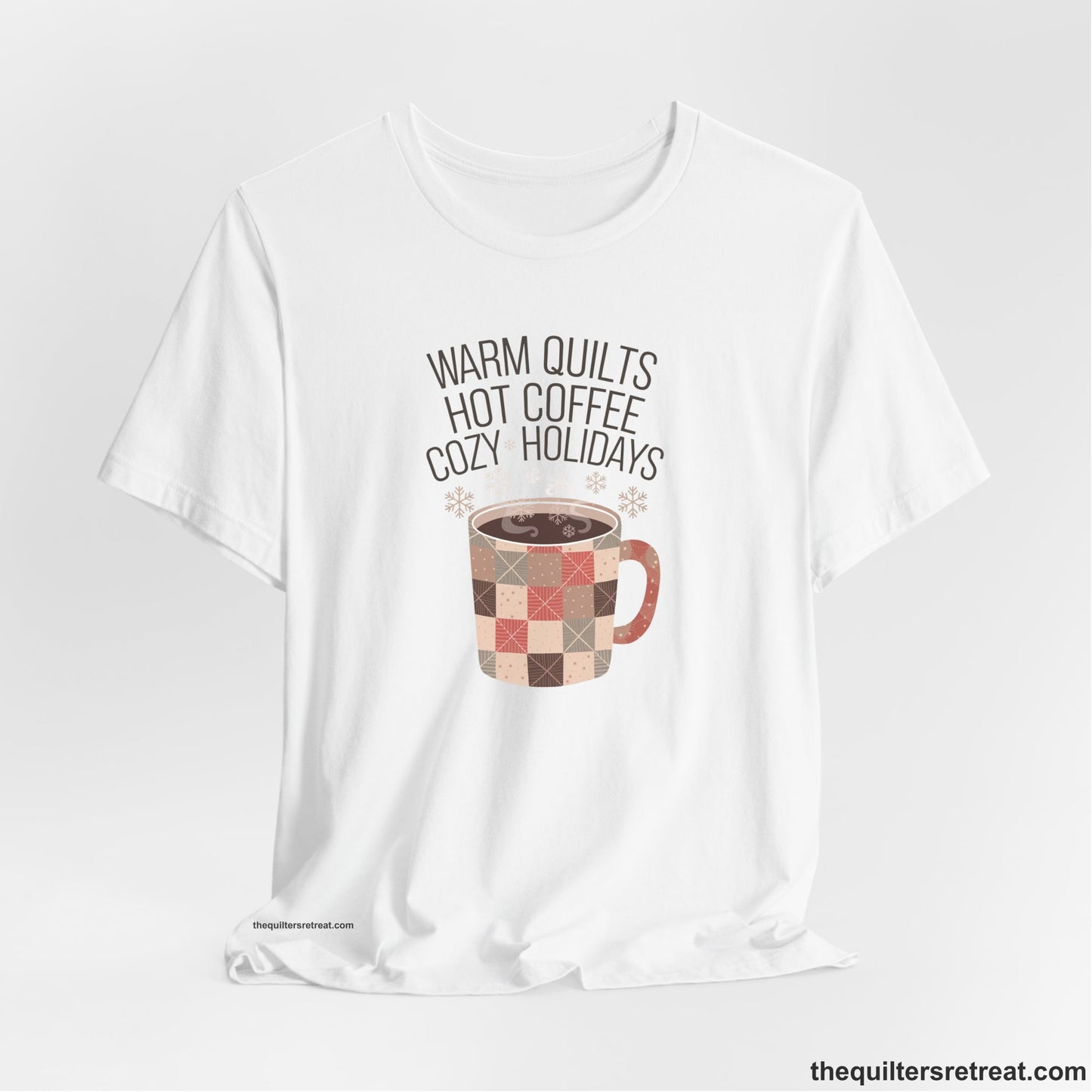 A White Short Sleeve T-Shirt with a warm quilts hot coffee cozy holidays text with a patchwork mug and snowflakes