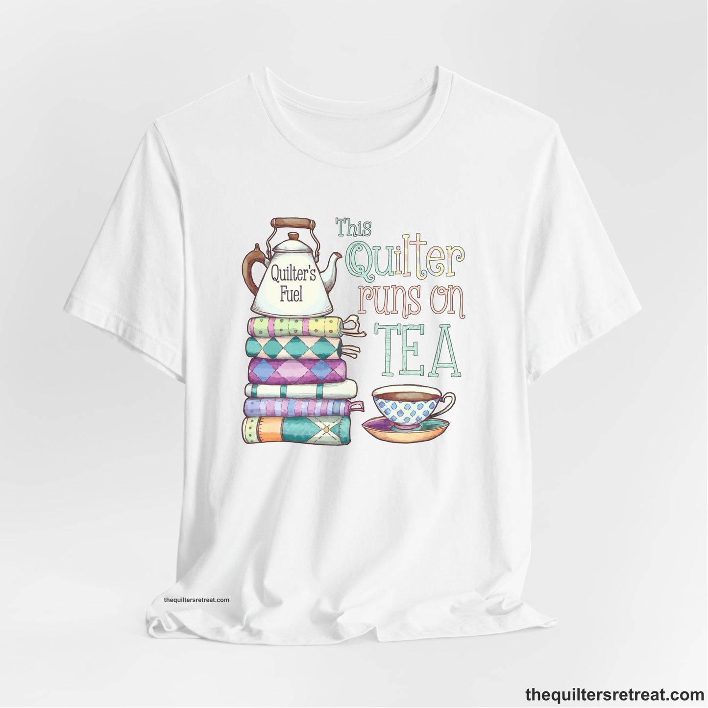 A White Short Sleeve T-Shirt with a stack of colorful quilts with teapot and cup, whimsical "This Quilter Runs on Tea" text