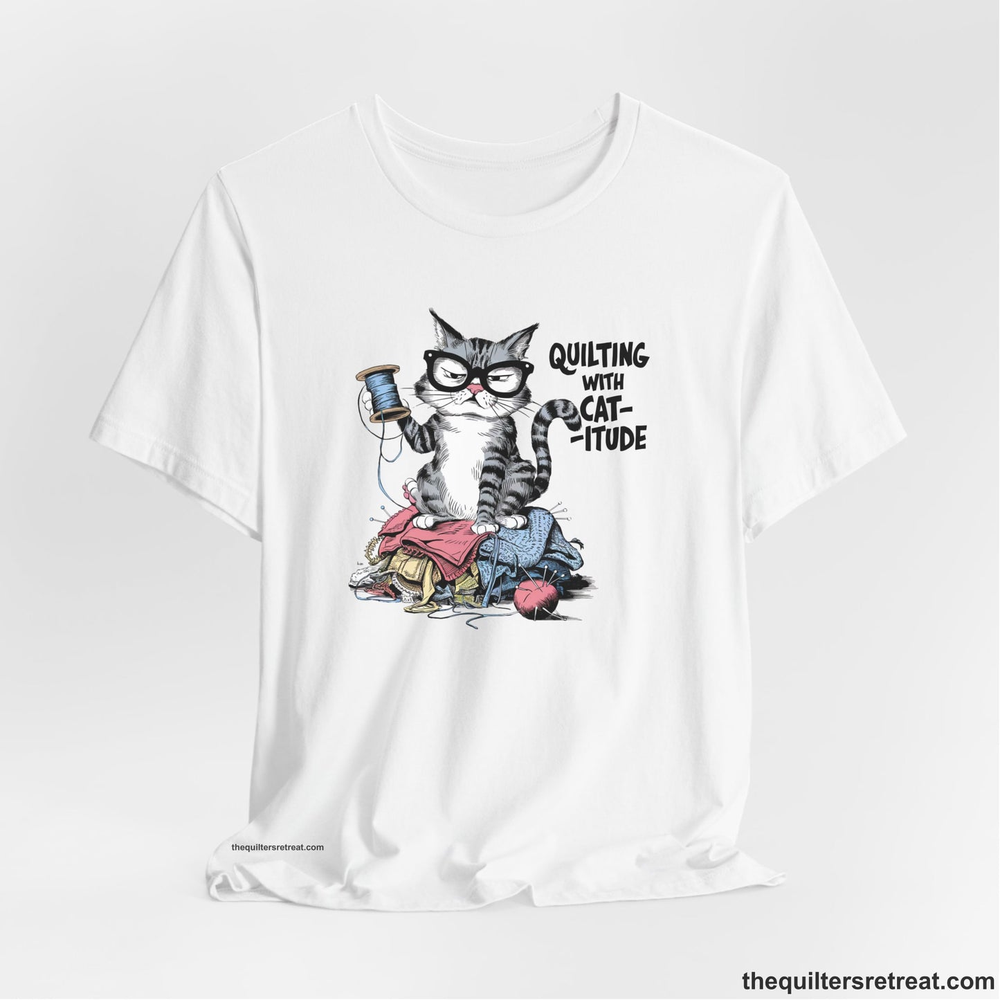 A White Short Sleeve T-Shirt with a grumpy cat holding thread spool atop fabric pile with "Quilting with Cat-itude" text