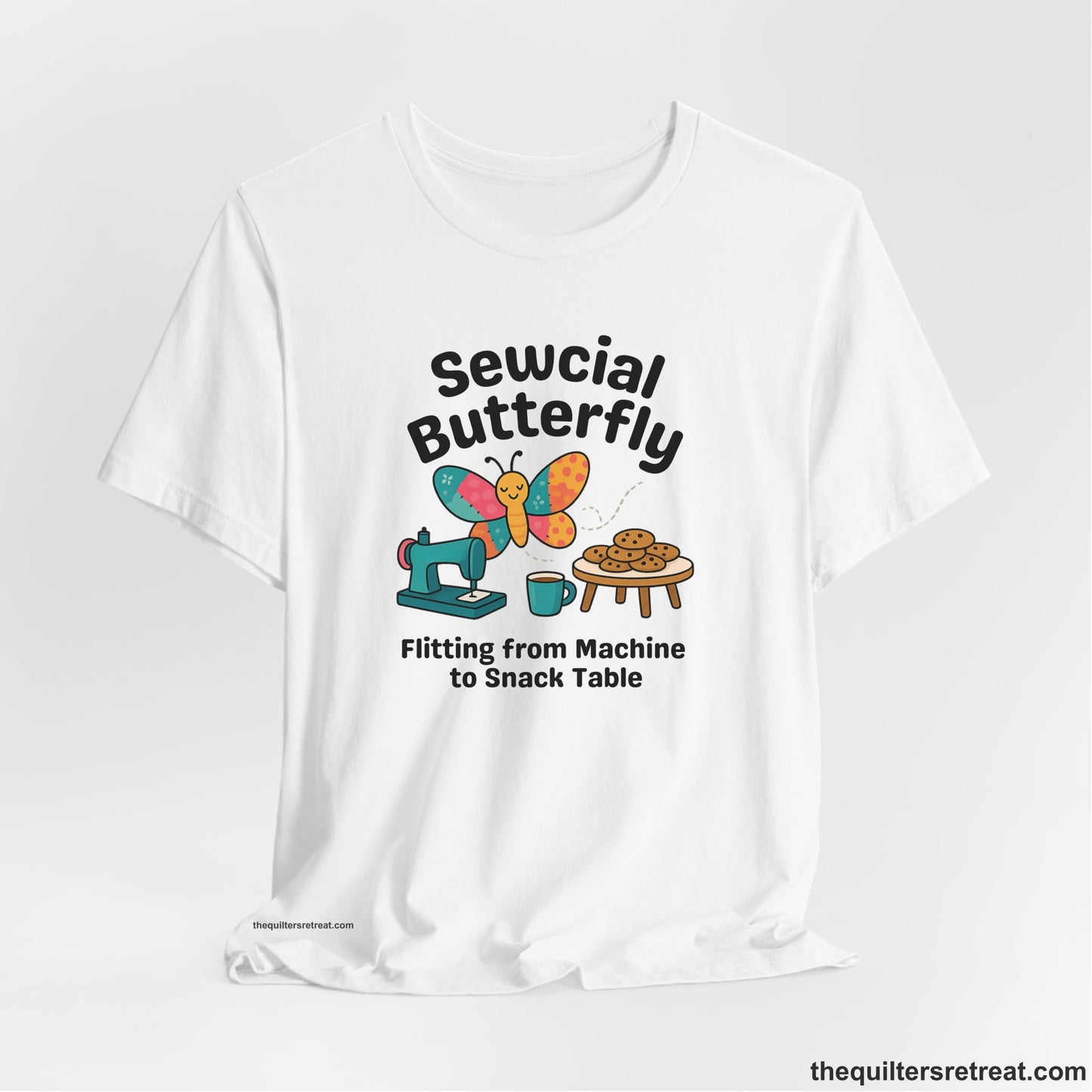A White Short Sleeve T-Shirt with a playful butterfly near sewing machine with cookies and coffee doodle design